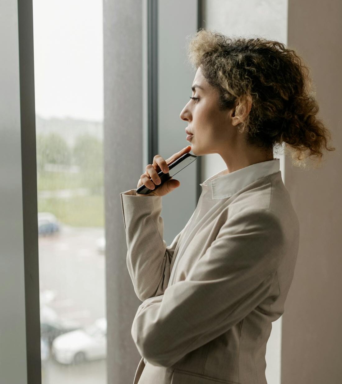 vrouw staat nadenkend bij raam en voelt zich vastzitten in haar hoofd.