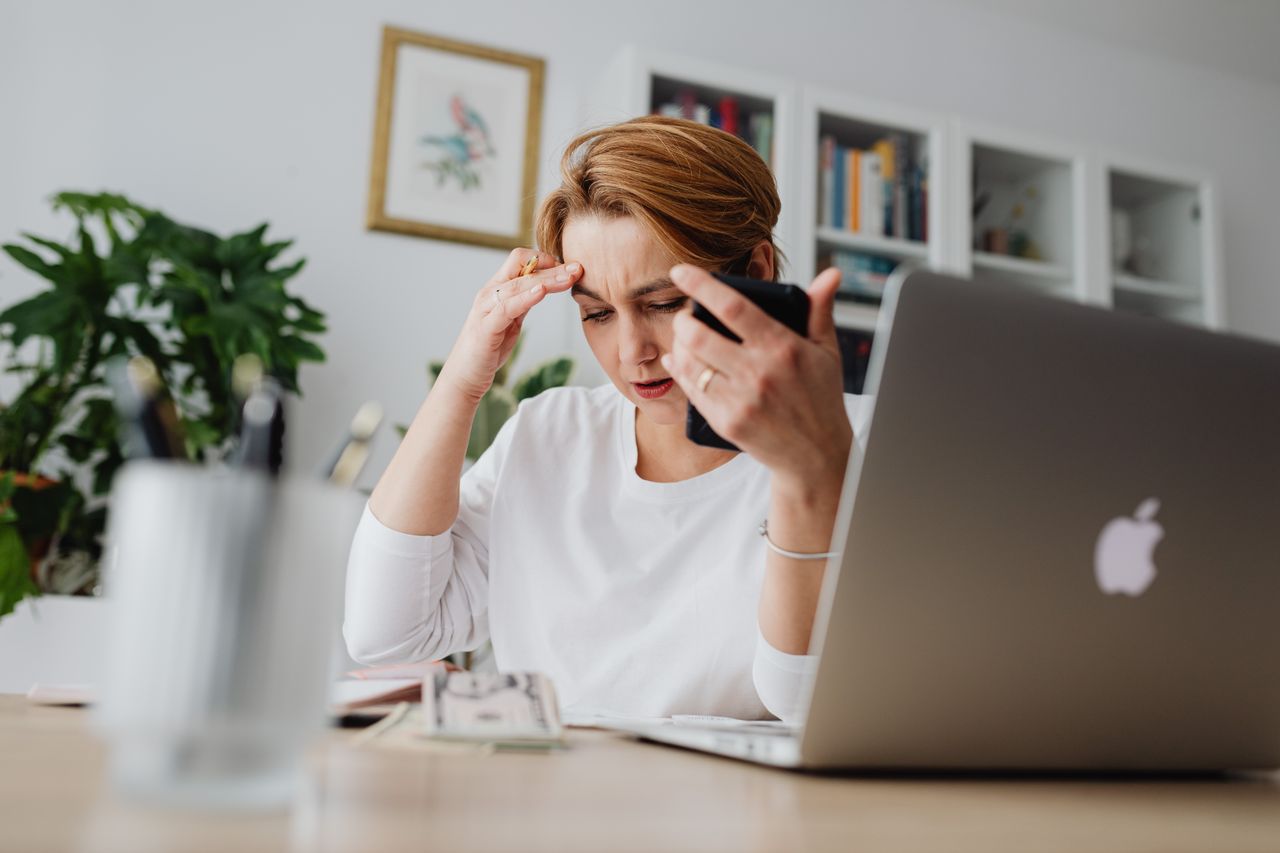 Vrouw zit nadenkend aan haar bureau, terwijl ze reflecteert op werk en privébalans.