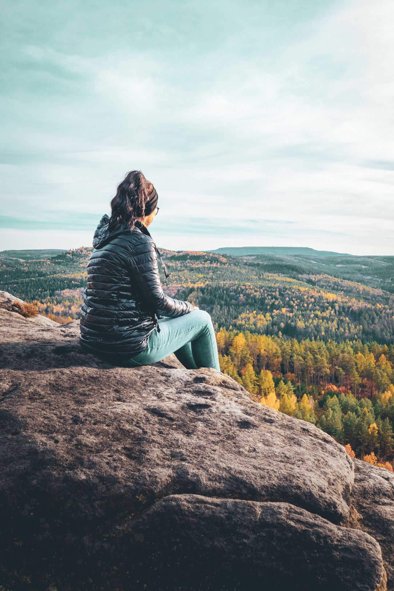 Vrouw kijkt vanaf een hoog uitkijkpunt uit over een landschap als symbool voor overzicht, bewustwording en een nieuw perspectief.