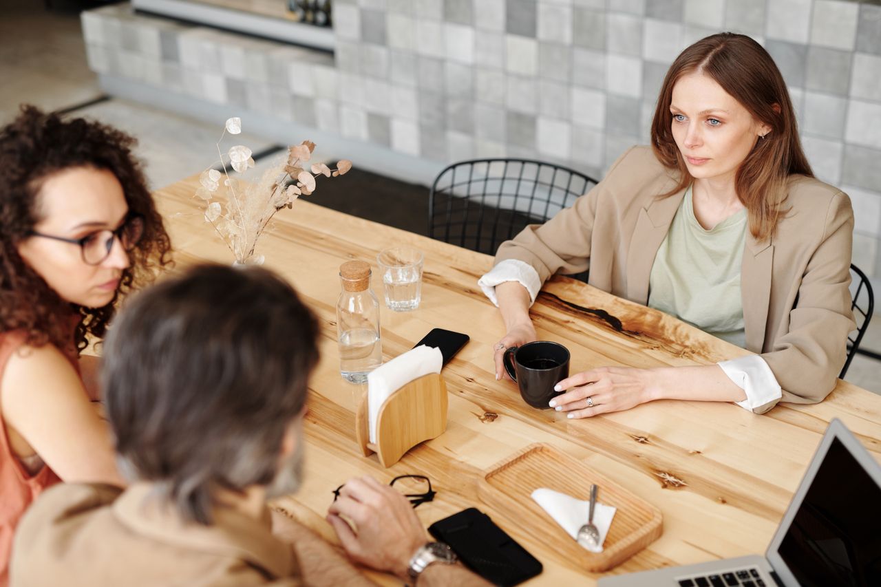 Vrouw voelt zich ongemakkelijk door de sfeer tijdens gesprek met twee anderen.