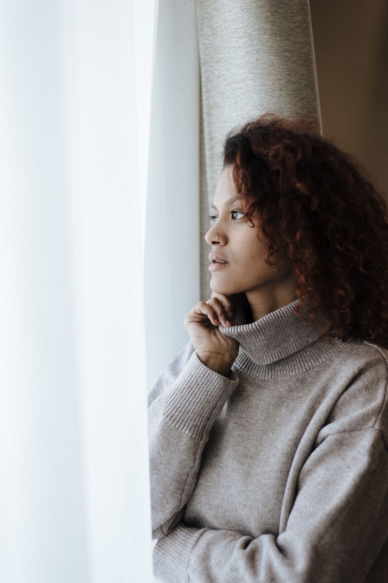 Een vrouw kijkt in gedachten naar buiten omdat ze iets voelt dat niet klopt.