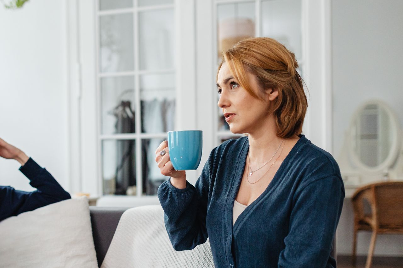 Vrouw luistert aandachtig naar een vriendin op de bank, terwijl haar eigen verhaal onbesproken blijft.