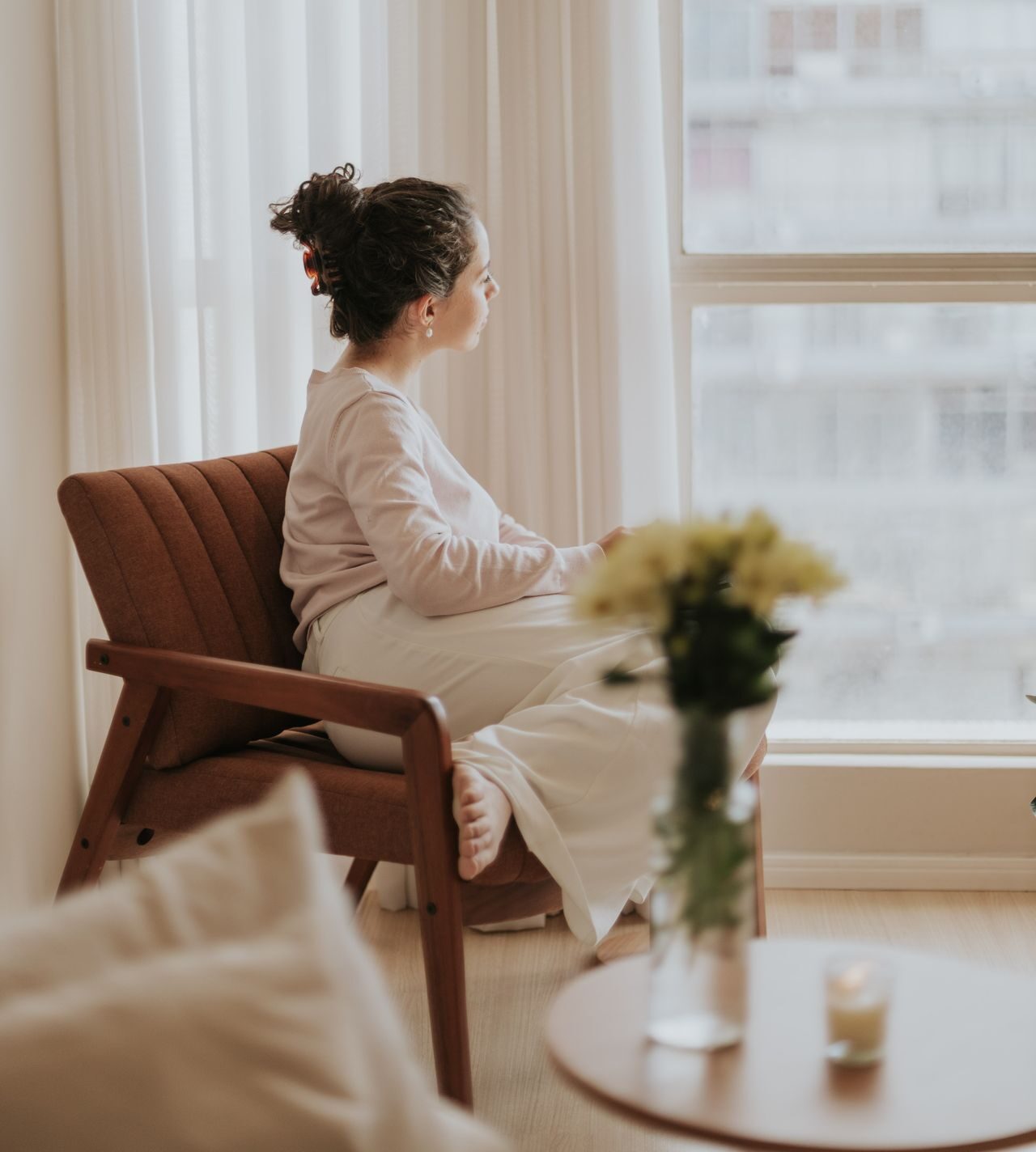 Vrouw zit rustig op een stoel, kijkt naar buiten en voelt of haar twijfel angst is of intuïtie