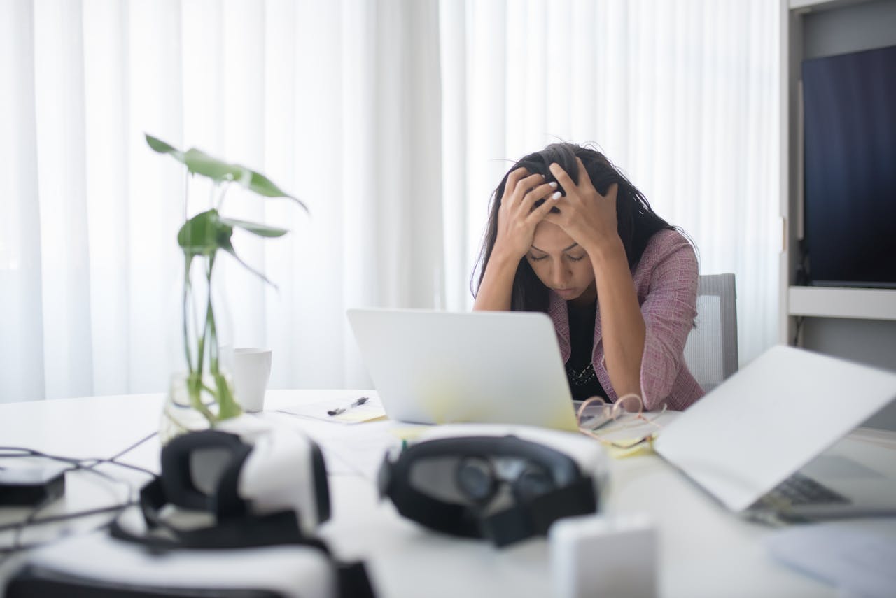 Vrouw achter haar bureau met hoofd in haar handen door stress en onrust.