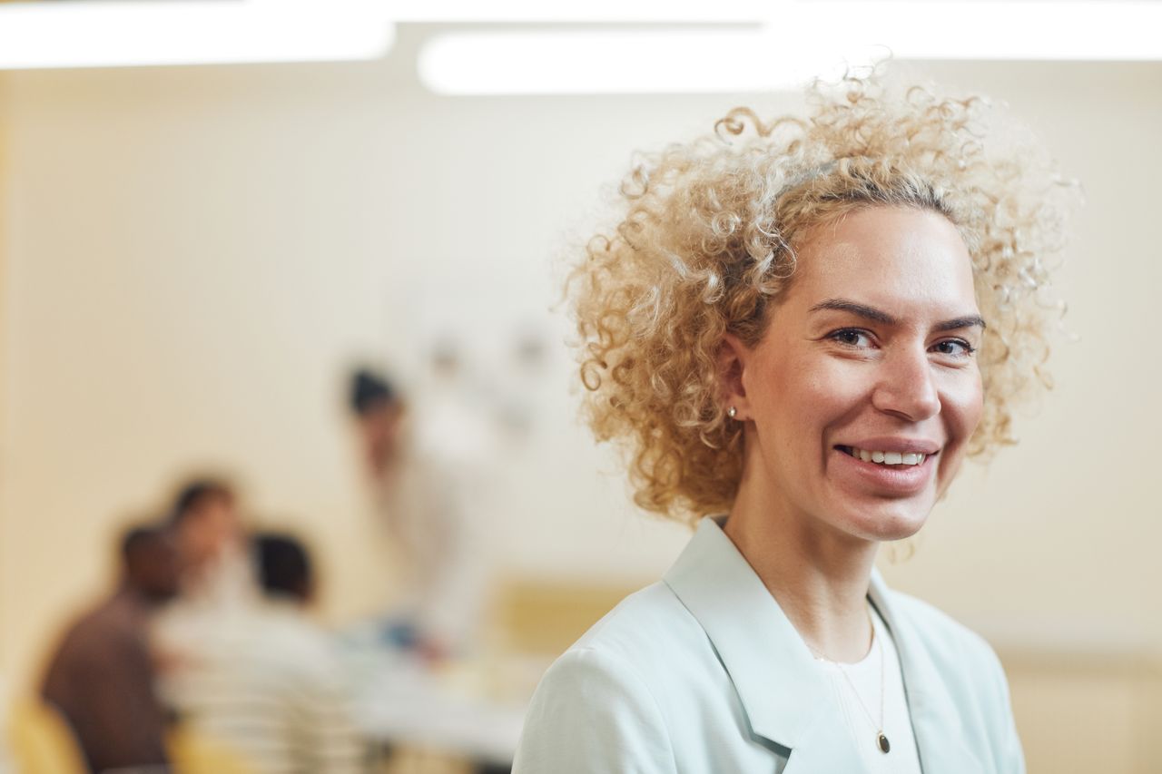Professionele vrouw straalt zelfvertrouwen en persoonlijk leiderschap uit in een werkomgeving.